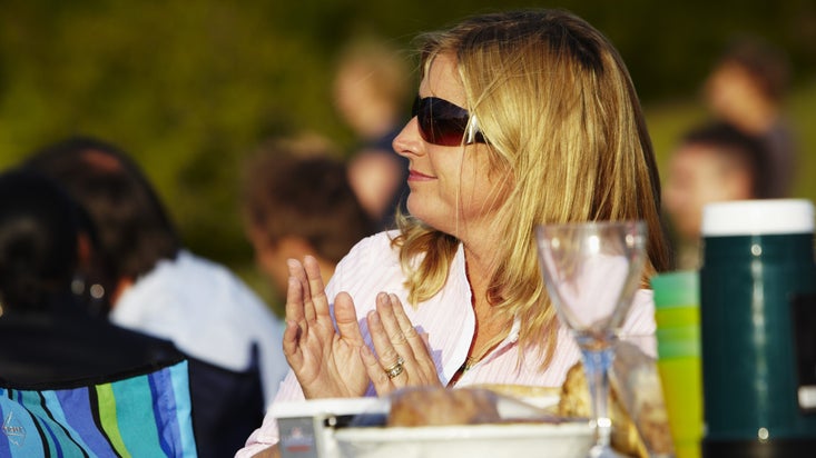 Seated woman clapping and enjoying a picnic